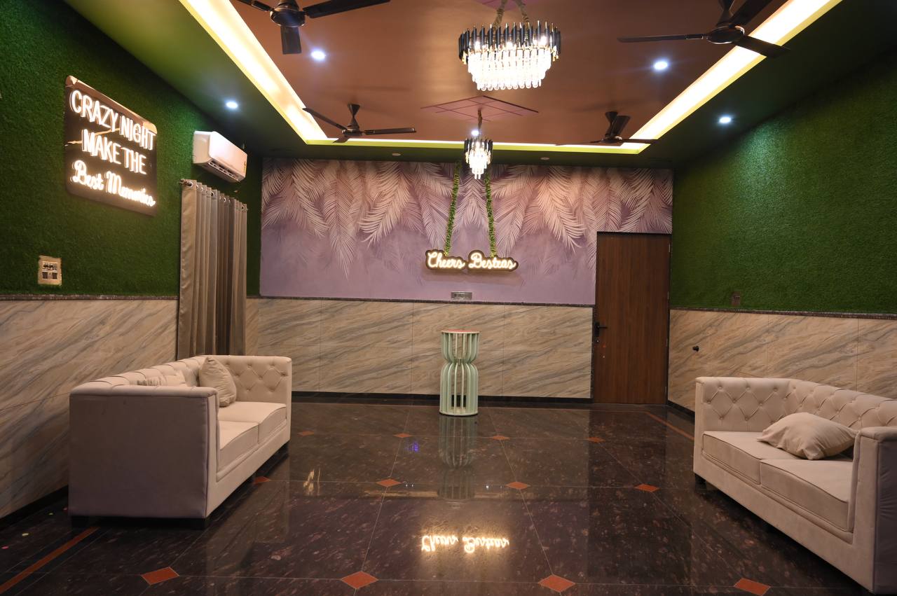 Decorated green lounge with cream sofas and ceiling lights.
