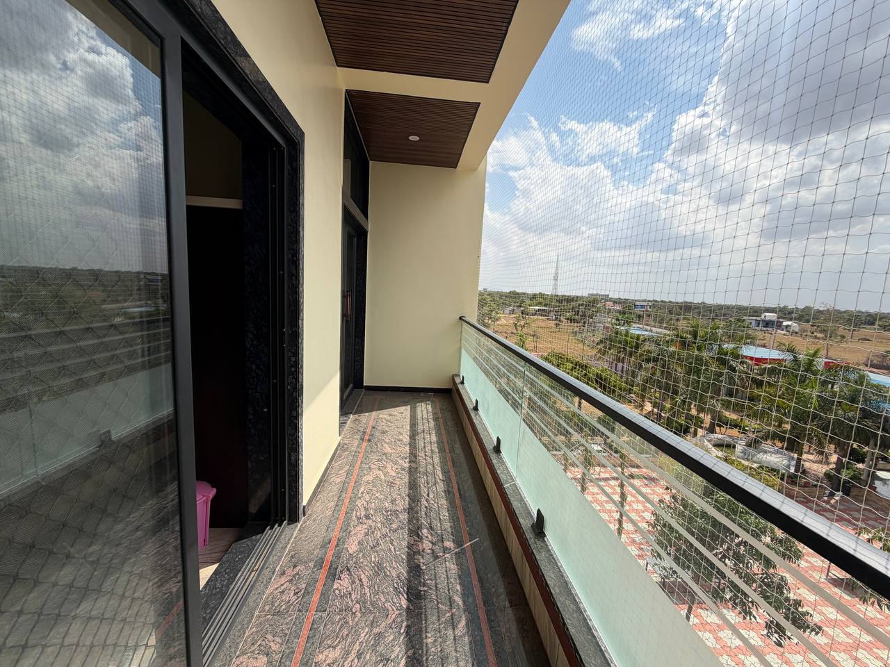 Covered balcony with protective netting and views over the property surroundings.